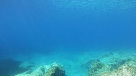 Sonnenstrahlen-Unter-Der-Meeresoberfläche-Mit-Klarem-Blauem-Wasser