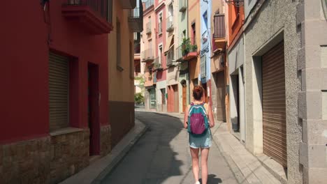 Back-view-of-beautiful-tourist-woman-walking-around-Castelló-d'Empúries-historic-center-in-Costa-Brava,-Spain---wide,-static-shot
