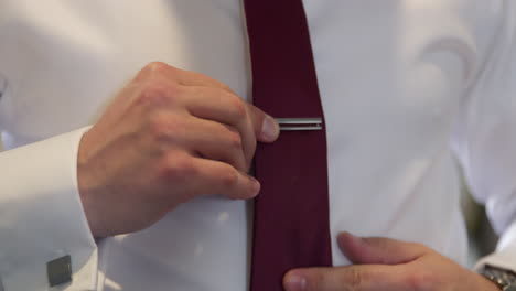 Lateinischer-Bräutigam-Im-Weißen-Hemd,-Das-Seine-Rote-Krawatte-Mit-Einem-Metallischen-Stangenclip-Anpasst