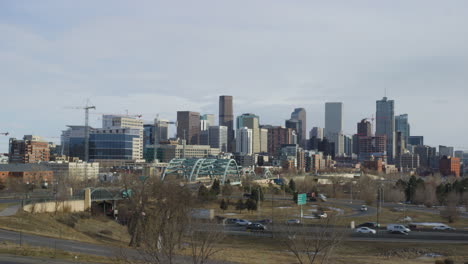 Downtown-Denver---Fahrzeuge-Fahren-Auf-Der-Straße-Mit-Hochhaus-Im-Hintergrund-In-Denver,-Colorado,-USA