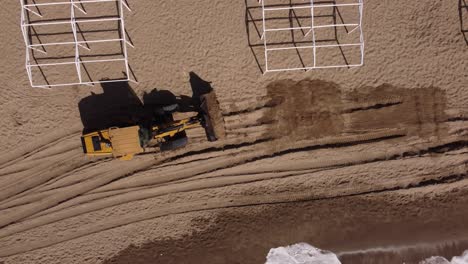 Aerial-top-down-shot-of-Excavator-transporting-new-sand-for-beach-during-sunlight