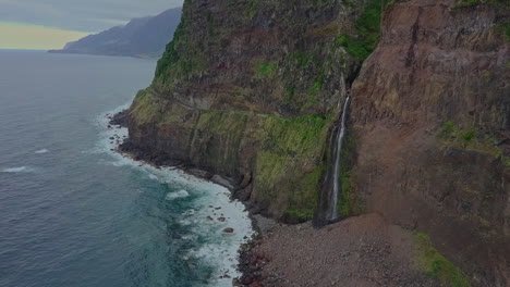 Beautiful-aerial-view-of-waterfall-flowing-into-the-ocean-from-mountainside