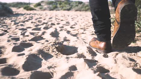 Man's-shoes-walking-through-the-sand-Detailed-Tracking-Shot