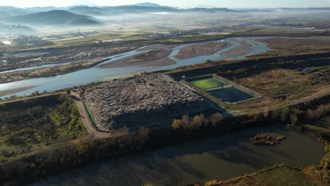 Large-landfill-with-unclassified-waste-on-river-bank,-dangerous-catastrophic-ecological-problem