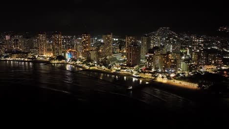 Timelapse-Nocturno-De-Drones-Aéreos-De-30-Fps-De-Las-Calles-De-La-Ciudad-De-Waikiki-Honolulu-Hawaii-Con-Palmeras-De-Tráfico-Y-Edificios-Con-Luces-De-La-Ciudad