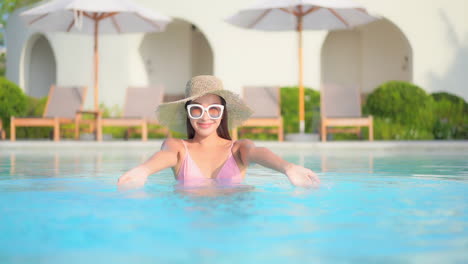 Happy-Exotic-Woman-Playing-With-Water-in-Swimming-Pool-of-Luxury-Hotel-Resort