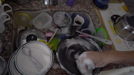 A-man's-hands-clean-a-pan-in-a-sink-full-of-dirty-dishes