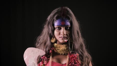 Live-Indian-Goddess-Kali-opens-her-eyes-and-looks-at-camera,-Indian-goddess-cosplay-with-long-hair-and-dark-background