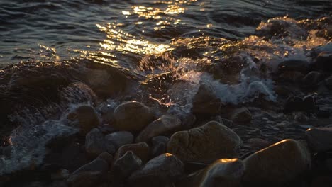 Ocean-water-waves-crashing-on-a-rocky-shoreline-at-sunset-on-rocks-on-the-coastline