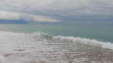 Coarse-sand-beach-sea-wave-in-slow-motion-at-120fps-4k-cloudy-day-turquoise-water-single-sea-waves-Big-empty-beach