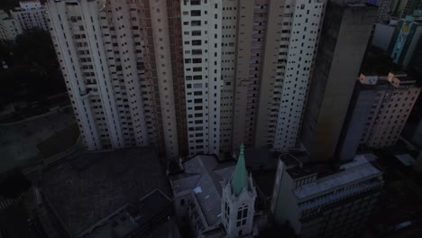 Inclinación-Aérea-De-Una-Iglesia-Y-Apartamentos-Deteriorados-Que-Revelan-La-Metrópolis-Iluminada-Por-El-Sol-De-La-Ciudad-De-Sao-Paulo