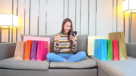 Thrilled-Expression-of-Young-Asian-Woman-When-She-Buying-Online-With-Smartphone-and-Credit-Bank-Card,-Full-Frame
