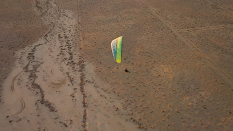 Flying-above-a-powered-paraglider-as-he-soars-over-the-Mojave-Desert-landscape-at-sunset