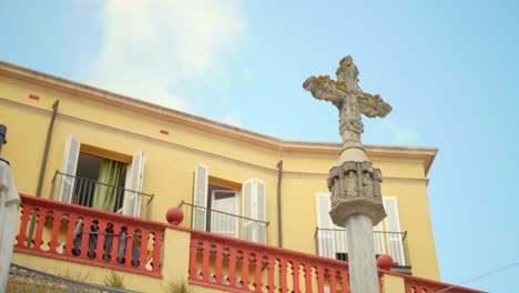 Old-And-Historic-Cross-In-Front-of-Spanish-Architecture-With-Blue-Sky-In-Background