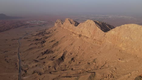 2021:-Rear-Drone-view-of-UAE's-Mleiha-Mountain-range-landscape,-Sharjah's-Mleiha-desert,-Mountains-in-the-United-Arab-Emirates,-4k-footage