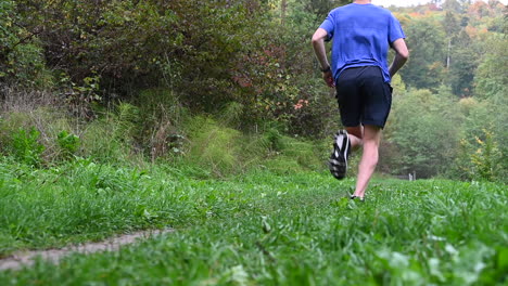 slow-motion,-a-young-athlete-with-a-blue-t-shirt-runs-in-the-nature,-defined-calves