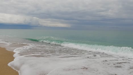 Coarse-sand-beach-sea-wave-in-slow-motion-at-120fps-4k-cloudy-day-turquoise-water-single-sea-waves-Big-empty-beach