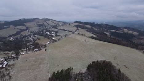 A-flight-over-the-countryside-with-a-path-leading-through-the-trees-and-a-view-of-the-surrounding-thing-during-the-beginning-of-the-snowfall