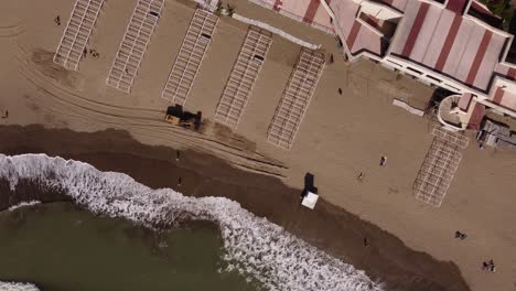 Aerial-top-down-of-Excavator-carrying-and-dropping-sand-on-the-beach-during-sunny-day,-Mar-del-Plata,Argentina