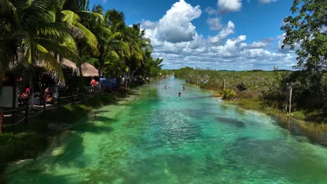Aerial-view-of-tourists-swimming-in-the-Rapidos-de-Bacalar,-in-Mexico---static,-drone-shot