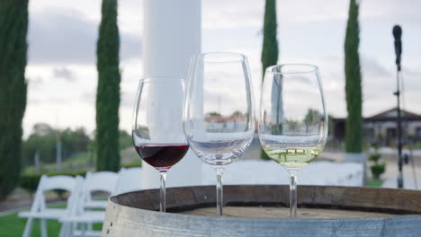 Three-glasses-of-water,-white-and-red-wine-on-a-barrel-in-the-garden-of-a-vineyard-during-an-event