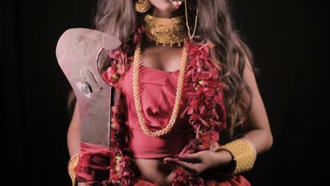 Lebende-Indische-Göttin-Kali-Schaut-In-Die-Kamera,-Indische-Göttin-Cosplay-Mit-Langen-Haaren-Und-Dunklem-Hintergrund,-Kameraneigungsaufnahme