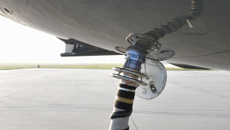 Air-Start-Unit-Discharge-Air-Hose-Attached-To-Aircraft-Underbelly,-Starting-Jet-Engine-On-The-Airfield