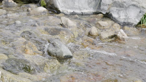 Close-up-shot-of-a-water-flowing-over-a-small-rocky-stream