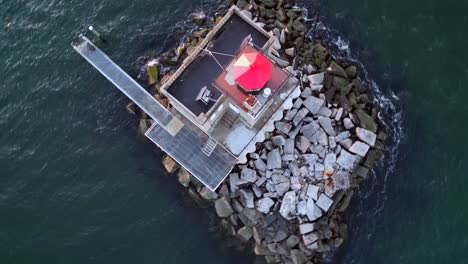 A-top-down,-aerial-view-of-the-Huntington-Harbor-Lighthouse-on-Long-Island,-NY-at-sunset