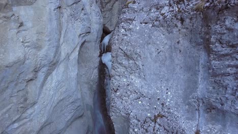 Aerial-crane-shot-descends-into-icy-vertical-waterfall-canyon,-winter