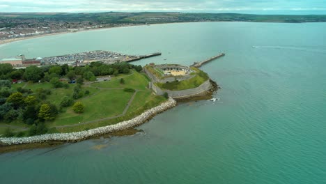Nothe-Fort-on-the-mouth-to-Weymouth-Harbour,-England---aerial-drone-shot