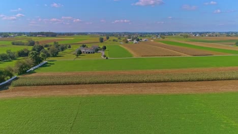 Eine-Luftaufnahme-Des-Ländlichen-Amerikas-Von-Amish-ackerland-Mit-Feldern,-Die-An-Einem-Sonnigen-Sommertag-Geerntet-Werden-Müssen