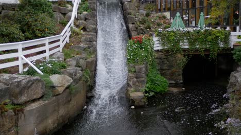 A-small-waterfall-runs-beside-a-patio-and-flowers