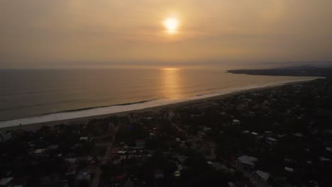 Backward-aerial-dolly-shot-with-the-sun-setting-over-the-ocean-at-Puerto-Escondido