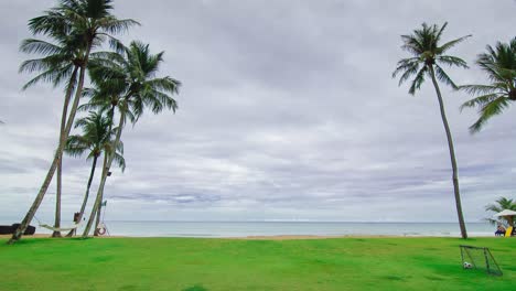 Der-Strand-Mit-Weißem-Sand,-Grünem-Rasen,-Kokospalmen-Und-Wellen-Vom-Ruhigen-Meer-Bei-Sonnenschein-Tagsüber