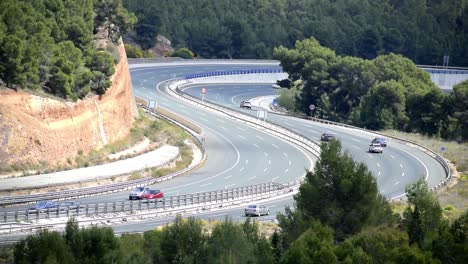 Cars-driving-on-a-winding-freeway-with-green-trees-surrounding