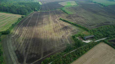 Gepflügtes-Landwirtschaftliches-Feld-Aus-Der-Luft-Mit-Wolkenschatten,-Die-über-Die-Landschaft-Ziehen
