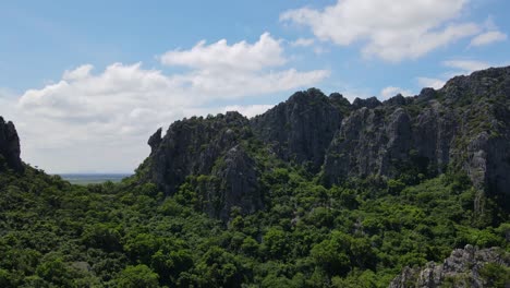 Reverse-aerial-footage-of-a-gorgeous-limestone-mountain-at-Wat-Khao-Daeng,-Khao-Sam-Roi-Yot-National-Park,-Phrachuap-Khiri-Khan,-Thailand