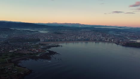 Gijon-drone-fly-above-the-city-in-north-of-Spain,-sunset-aerial-view-of-sand-beach-tourist-holiday-destination