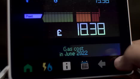 Close-Up-Of-Finger-Pressing-Touchscreen-Display-Of-UK-Energy-Smart-Meter-To-Check-Cost-Of-Gas-Usage-By-Month-In-2022