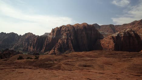 Beautiful-landscape-nature-shot-of-stunning-red-rock-formations-with-dried-petrified-sand-dunes-below-on-a-hike-in-Snow-Canyon-State-Park,-Utah-on-a-warm-sunny-summer-day