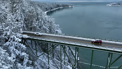 Static-drone-shot-of-cars-leaving-a-a-steel-bridge-and-entering-the-mainland-covered-in-snow