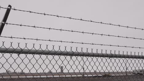 A-barbed-wire-and-chain-link-fence-with-an-airport-control-tower-in-the-background