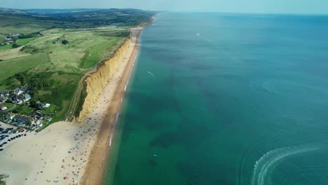 Bridport-West-bay-cliffs-above-British-seaside-turquoise-ocean-coastline-aerial-view,-Dorset