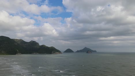 Steady-aerial-footage-of-these-islands-and-mountain-as-the-waves-rush-to-the-shore-during-the-morning-then-sunlight-go-through-gray-clouds,-Sam-Roi-Yot-National-Park,-Prachuap-Khiri-Khan,-Thailand