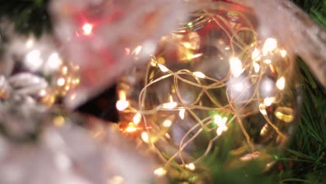 Transparent-christmas-ball-with-lights,-hanging-from-the-christmas-tree