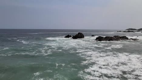 Flying-above-waves-with-view-of-rocks-in-Mazunte,-Oaxaca,-Mexico