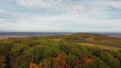 Flug-über-Einen-Herbstlichen-Wald-Auf-Einem-Hügel-Mit-Feldern-Und-Dörfern-Im-Hintergrund