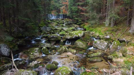 flying-above-a-river-bed-with-boulders-in-a-forest-in-Jizera-mountains,-Czechia