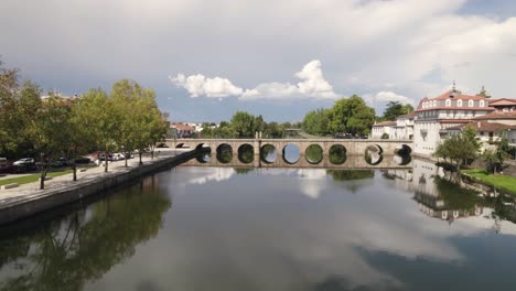 Clouds-reflected-on-Tamega-River,-flight-approaching-Roman-Bridge,-Chaves,-Portugal